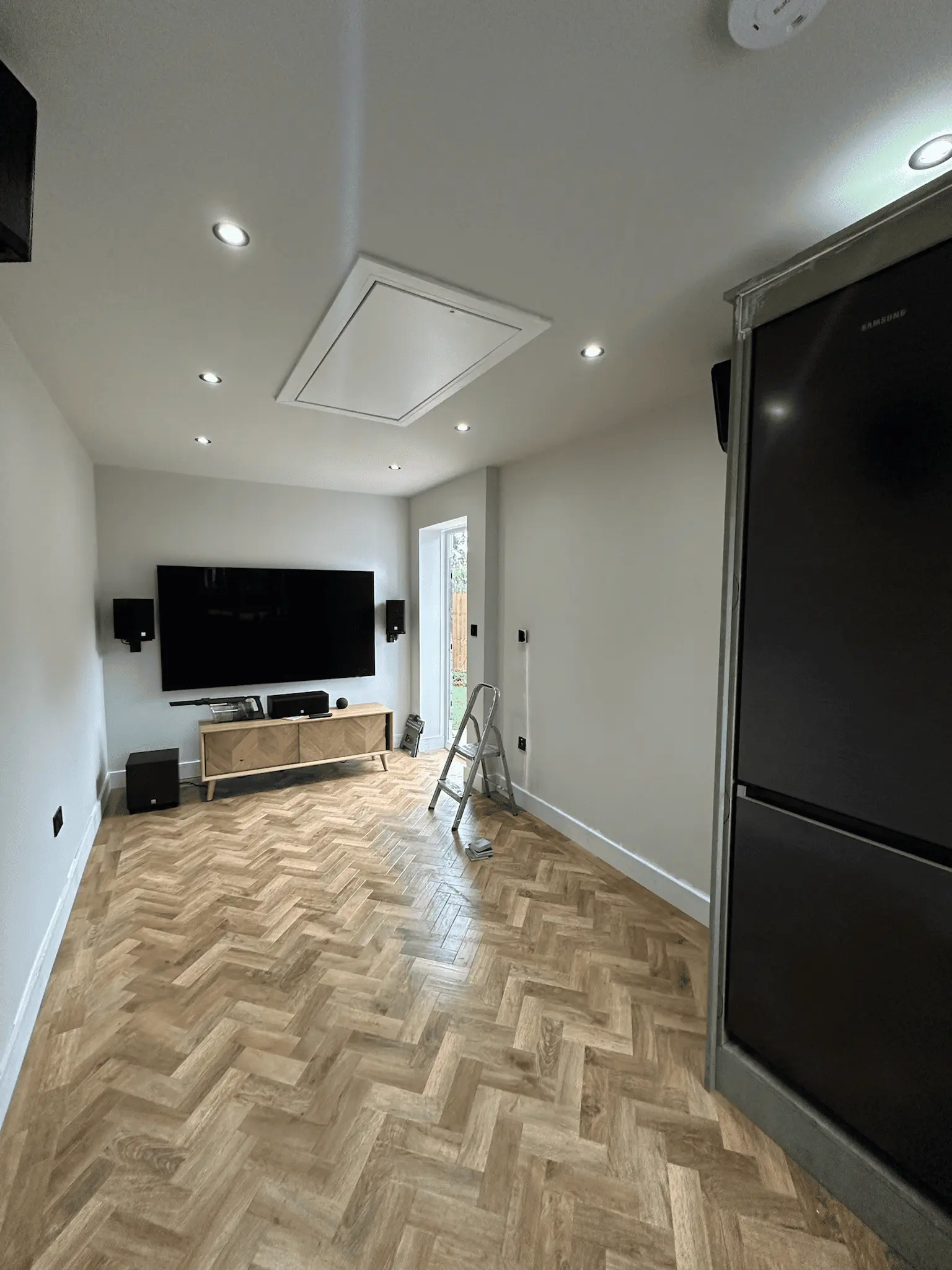 Garage converted into a cinema room with a wall-mounted TV and herringbone floor
